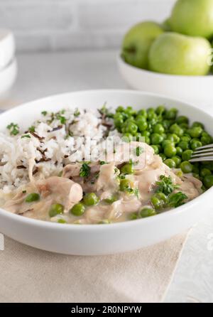 Fricassée de poulet avec basmati, riz sauvage et pois verts beurrés sur une assiette Banque D'Images