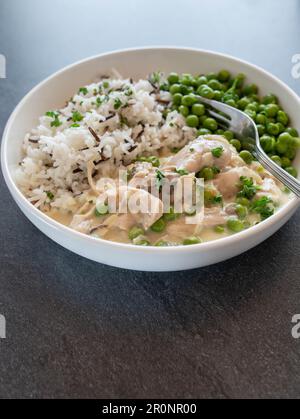 Fricassée de poulet avec basmati, riz sauvage et pois verts beurrés sur une assiette Banque D'Images