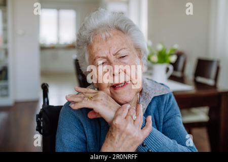 Portrait d'une femme âgée en fauteuil roulant avec douleur dans la main. Banque D'Images