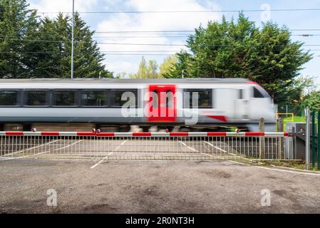 British Rail classe 720 le train Aventra de Greater Anglia passe à vitesse supérieure au passage à niveau de Church Lane. Passage à niveau avec barrières en bas dans la zone rurale Banque D'Images