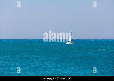 Un voilier blanc navigue dans l'océan bleu calme Banque D'Images