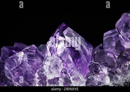 cristal violet amehtyst sur fond noir. arrière-plan de texture de détail de macro. gros plan brut brut non poli semi-précieuse pierre Banque D'Images