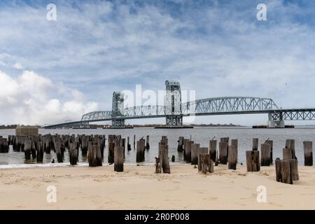 Vue depuis la plage de Breezy point, NY, USA, avec des restes de poteaux de la jetée vers la levée verticale Marine Parkway–Gil Hodges Memorial Bridge Banque D'Images