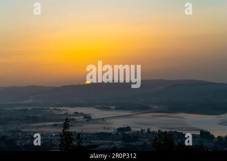 Vue panoramique de haut niveau sur la rivière Limia près de Viana do Castelo, Portugal principalement couvert de brume et de brume basse avec le soleil orange Banque D'Images