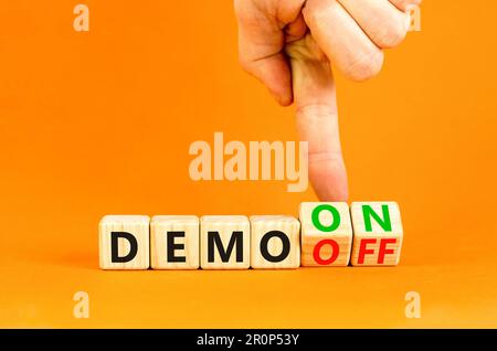 Symbole Démo activé ou désactivé. Homme d'affaires transforme les cubes en bois et le mot Démo désactivé en Démo activée. Belle table orange fond orange. Affaires et dem Banque D'Images
