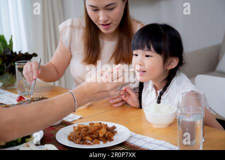 Bonheur famille asiatique mère et père et fille manger de la nourriture dans la cuisine ensemble à la maison, parent et enfant assis manger dans la salle de séjour, liant a Banque D'Images