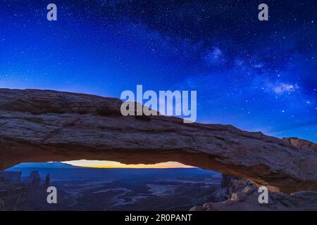 Une exposition longue et unique de la voie lactée au-dessus de Mesa Arch et de la lumière avant l'aube à l'horizon dans le parc national de Canyonlands, Utah. Banque D'Images