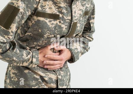 Jeune homme hispanique portant l'uniforme militaire de camouflage avec la main sur l'estomac parce que la nausée, la maladie douloureuse sentiment malaise. concept ache Banque D'Images