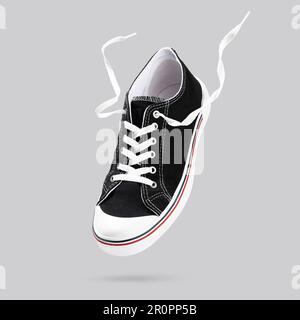 Baskets noires volantes isolées sur fond gris. Chaussures de sport tendance et élégantes. Design minimaliste et créatif avec chaussures. Faites une maquette pour yo Banque D'Images