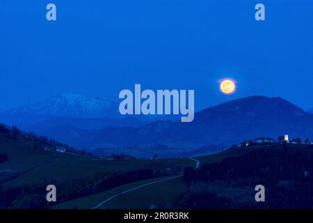 Waidhofen an der Ybbs : pleine lune s'élève à la montagne Ötscher (à gauche), hameau et église Windhag, arbres de poire en fleurs, prairies, maisons de ferme à Mostvierte Banque D'Images