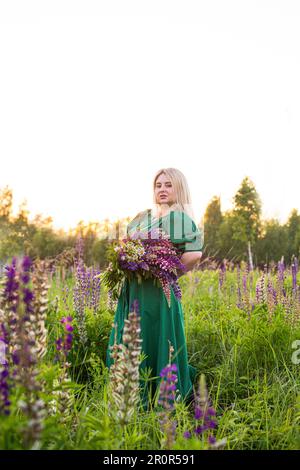 portrait d'une fille dans un champ fleuri au soleil au coucher du soleil Banque D'Images