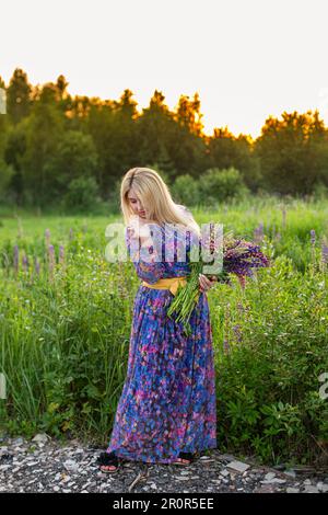 portrait d'une fille dans un champ fleuri au soleil au coucher du soleil Banque D'Images