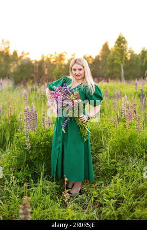 portrait d'une fille dans un champ fleuri au soleil au coucher du soleil Banque D'Images