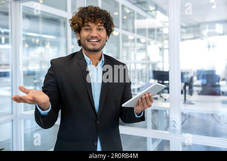Jeune et réussi programmeur masculin, portrait d'un homme ingénieur avec un employé de démarrage d'ordinateur de tablette travaillant à l'intérieur du bâtiment de bureau utilisant une tablette pour tester des applications souriant regardant la caméra Banque D'Images