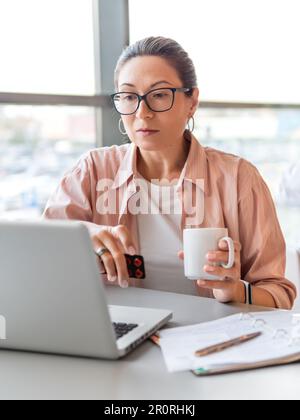 Femme consciente avec des pilules de médicaments. Travailler avec un ordinateur portable. Problèmes de santé mentale, épuisement émotionnel ou maux de tête. Bureau moderne au centre de travail. Wor Banque D'Images