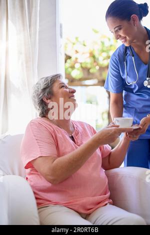 Merci d'avoir fait de moi un petit placard si charmant. un soignant offrant une tasse de thé à un patient âgé dans une maison de soins infirmiers. Banque D'Images
