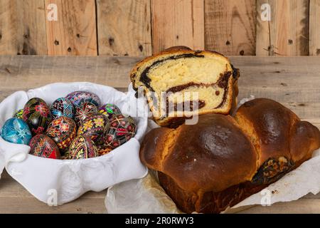 Gâteaux roumains fraîchement cuits et œufs de Pâques peints à la main. 'Cozonac' ou 'cozonaci' est fait de pâte de levure douce utilisée pour faire des holos traditionnels Banque D'Images