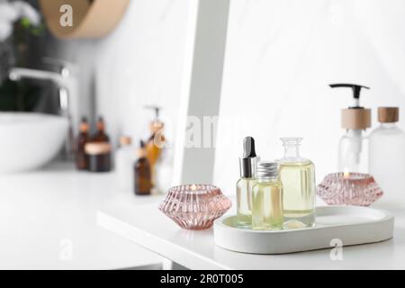 Huiles essentielles et bougies sur étagère blanche dans la salle de bains. Espace pour le texte Banque D'Images