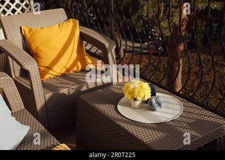 Coussin orange et fleurs de chrysanthème jaune sur meubles de jardin en rotin à l'extérieur Banque D'Images