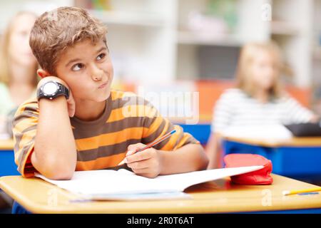 Un environnement stimulant pour faire ressortir le meilleur de votre enfant. Jeune écolier pensant vraiment dur à une question difficile dans un test - copyspace. Banque D'Images