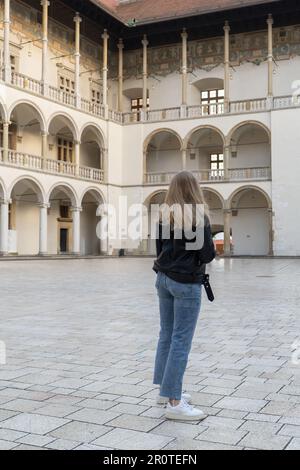 Une femme voyageur dans des lieux historiques regarde autour de la cour d'un monument dans le château de Krakow Wawel. Tourisme dans un lieu historique le jour ensoleillé. Femme Tourisme et blogging partage en direct en ligne pour le voyage de l'auditoire ensemble Banque D'Images