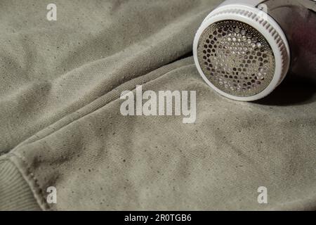 Rasoir anti-pilling. Appareil pour le rasage des vêtements de pellets. Rasoir en tissu anti-peluche. Chandail électrique portable en pillule défuzzer l'enpeluchage du pull en acrylique ou en laine. Mode de vie durable, réduisant le recyclage des déchets de vêtements Banque D'Images