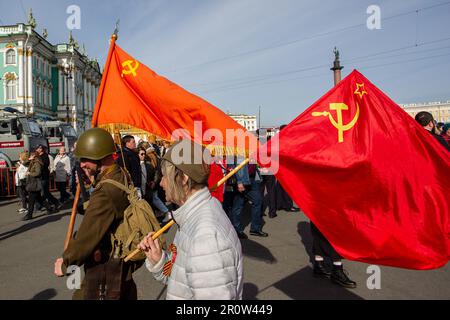 Un homme et une femme avec les drapeaux de l'Union soviétique marchent le long de la place du Palais lors d'une célébration du jour de la victoire à l'échelle de la ville. La Russie a célébré en 78th l'anniversaire de la victoire complète et finale de la Grande guerre patriotique contre l'Allemagne nazie. Le jour de la victoire a été célébré dans de nombreuses villes du pays sur 9 mai, dont les principales étaient Saint-Pétersbourg et Moscou. Des milliers de personnes à Saint-Pétersbourg sont descendues dans les rues de la ville pour honorer les victimes de la Seconde Guerre mondiale La Russie a célébré en 78th l'anniversaire de la victoire complète et finale de la Grande guerre patriotique contre l'Allemagne nazie. Victoire D Banque D'Images