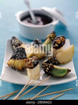 Fondue de fruits frais avec chocolat au lait fondu et fruits secs écrasés et noix Banque D'Images