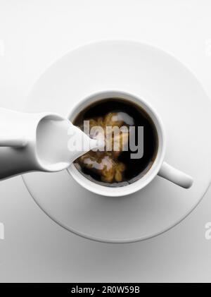 L'ajout de lait dans une tasse de café Banque D'Images