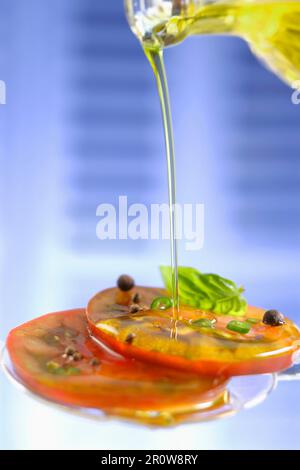 Verser l'huile d'olive sur les tomates tranchées Banque D'Images