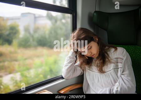 Adolescente dormant dans le train pendant le voyage Banque D'Images