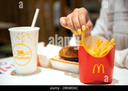 VARSOVIE, POLOGNE - 04 SEPTEMBRE 2022 : femme avec des frites McDonald's, hamburgers et boissons à table dans un café, en gros plan Banque D'Images