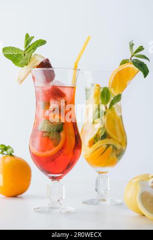 Cocktails frais d'été avec des morceaux de fraise, citron et orange, menthe isolée sur blanc Banque D'Images