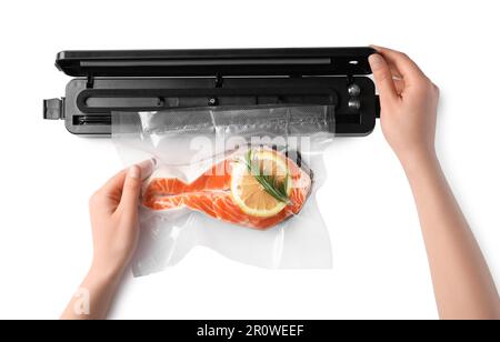 Femme utilisant un scelleuse sous vide sur fond blanc, vue de dessus. Saumon avec citron en paquet Banque D'Images