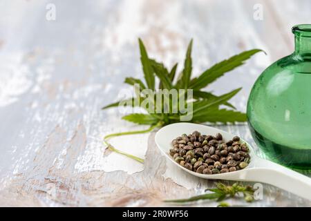 Feuilles de chanvre, graines de chanvre sur cuillère et huile de chanvre en bouteille en verre Banque D'Images