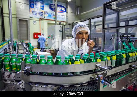 Province d'Almaty, Kazakhstan - 06 juin 2012 : usine de lait Danone. Jeune opérateur asiatique sur la ligne de convoyeur de yogourt Banque D'Images