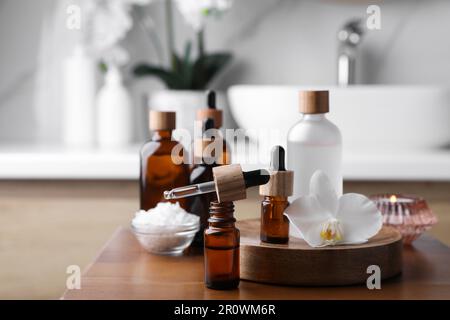 Huiles essentielles, fleurs d'orchidées et sel de mer sur une table en bois dans la salle de bains Banque D'Images