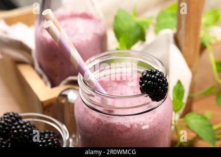 Différents verres de délicieux smoothie blackberry et de baies fraîches sur fond de bois, gros plan Banque D'Images