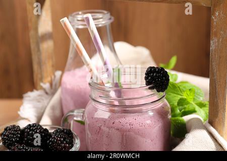 Différents verres de délicieux smoothie blackberry et de baies fraîches sur fond de bois, gros plan Banque D'Images