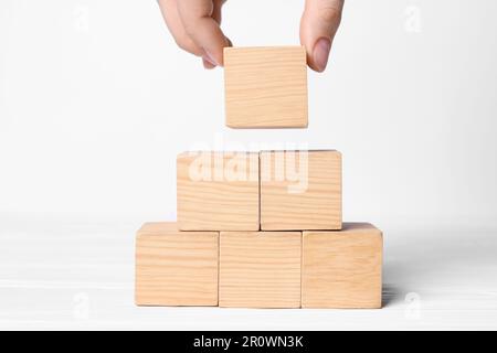 Femme construisant une pyramide de cubes sur fond blanc, gros plan avec de l'espace pour le texte. Concept d'idée Banque D'Images