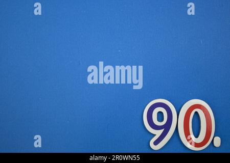 Le numéro 90, placé sur le bord d'un fond bleu, photographié par le dessus, de couleur bleu clair et rouge. Banque D'Images