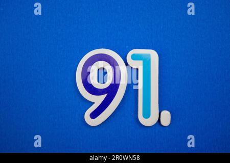 Le numéro 91 de couleur bleu clair, photographié par le dessus, placé sur un fond bleu. Banque D'Images