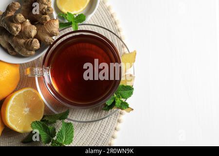 Tasse de délicieux thé au gingembre, feuilles de menthe et citrons sur table en bois blanc, vue du dessus. Espace pour le texte Banque D'Images