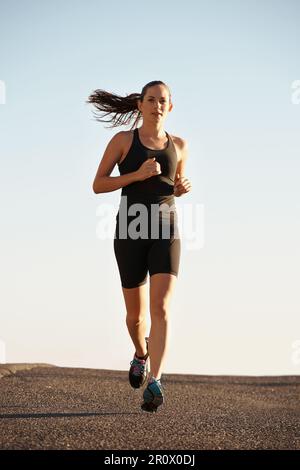 Exécution rapide et gratuite. une jeune femme qui court le long d'une route. Banque D'Images