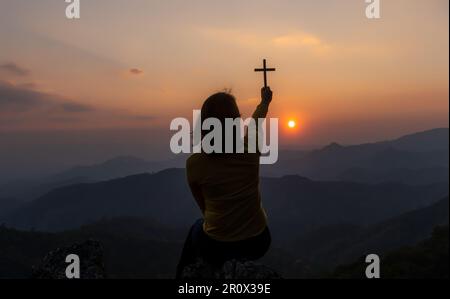 Femme en prière chrétienne culte au coucher du soleil. Mains jointes en prière. adorer Dieu avec conception chrétienne de la religion. Banque D'Images