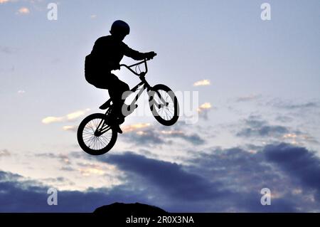 Silhouette d'un cavalier BMX de saut Banque D'Images