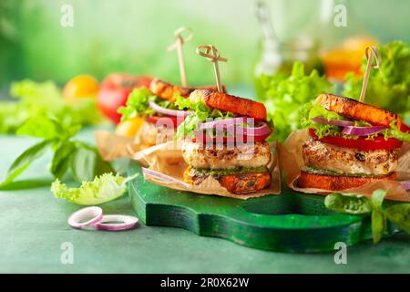 Délicieux hamburger de dinde de citrouille rôtie avec tomates et pesto sur bois vert. Banque D'Images