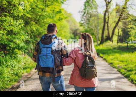 Couple heureux randonnée dans la nature par beau temps. Couple tenant les mains et marchant sur la route. Banque D'Images