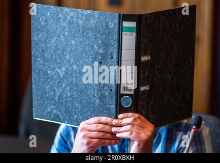 Schwerin, Allemagne. 10th mai 2023. Le défendeur, âgé de 32 ans, détient un dossier devant son visage à côté de son avocat Thomas Ruppel au début du procès au sujet de l'incendie dans un refuge pour réfugiés pour Ukrainiens à Groß Strömkendorf dans la salle d'audience du tribunal régional. Selon la poursuite, le pompier présumé est responsable de toute une série d'incendies. Personne n'a été blessé dans l'incendie le 19 octobre 2022, et les 14 résidents et leurs soignants ont pu s'échapper à temps vers la sécurité. Credit: Jens Büttner/dpa/Alay Live News Banque D'Images