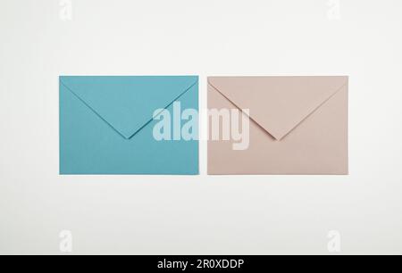 Vue de dessus des enveloppes roses et bleues sur fond blanc. Deux enveloppes, postées à plat. Copier l'espace. Banque D'Images